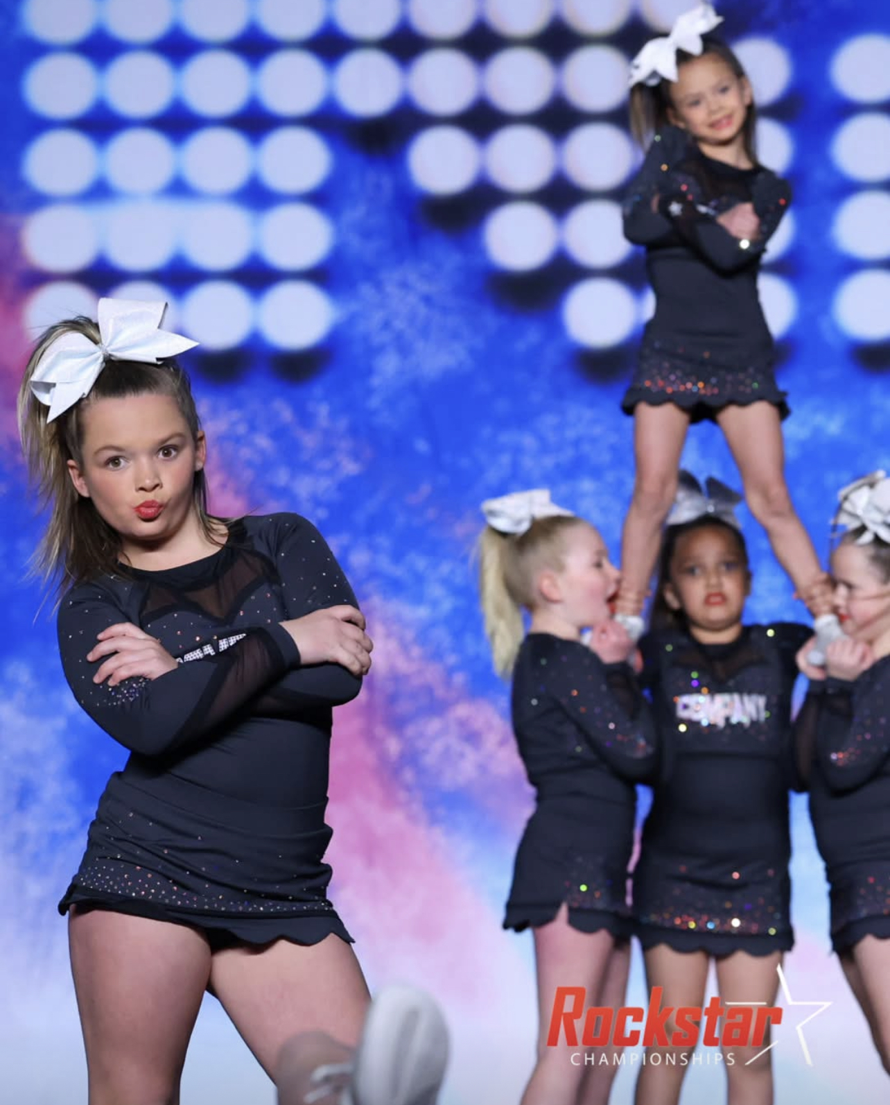 Group of dancers in matching black outfits performing on stage